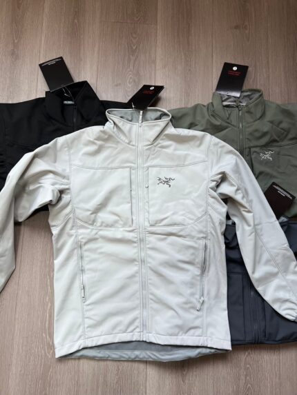 Giacche outdoor eleganti dai colori vari su superficie in legno, pronti per ogni avventura.