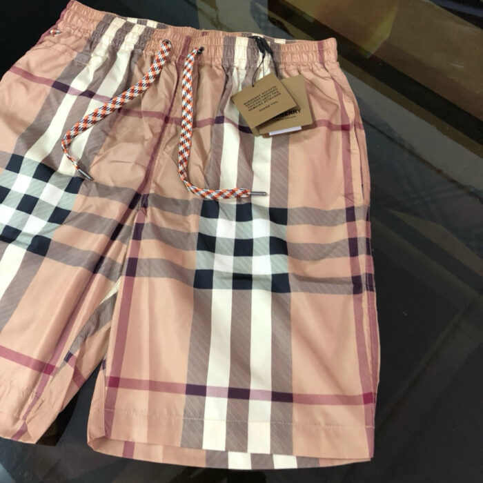 Pantaloncini da spiaggia quadrettati con cintura elasticata e cordini decorativi, stile casual e estivo.
