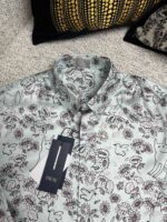 Camicia dai motivi floreali e animali, stile casual e creativo, su sfondo testurizzato morbido.