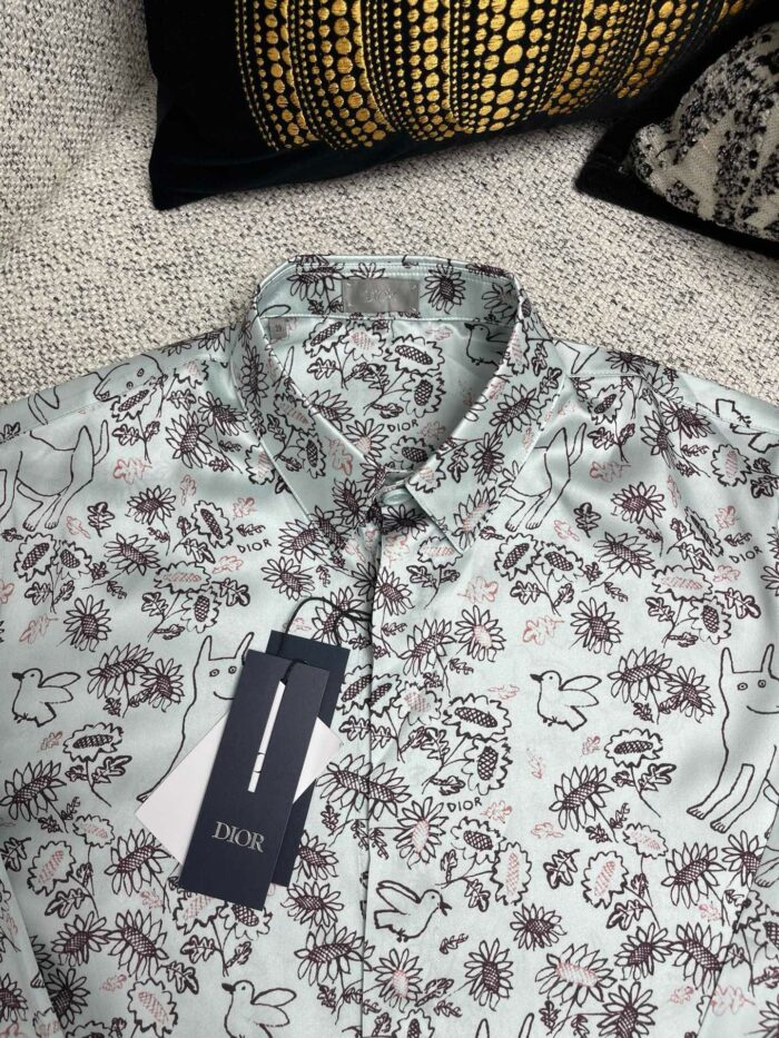 Camicia dai motivi floreali e animali, stile casual e creativo, su sfondo testurizzato morbido.