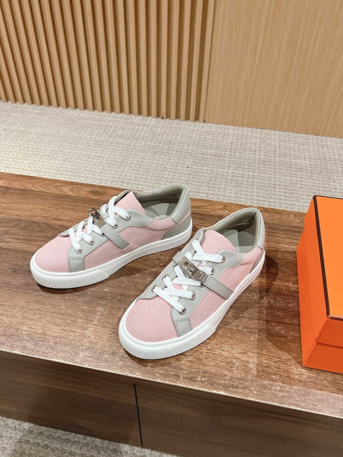 Sneaker trendy rosa e verde su superficie in legno con dettagli bianchi, stile casual e moderno.