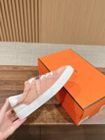 Sneaker rosa pastello in suede con suola bianca, scatola arancione elegante e stile moderno.