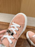 Sneaker rosa pastello in suede con lacci bianchi e dettaglio metallico, elegante e trendy.