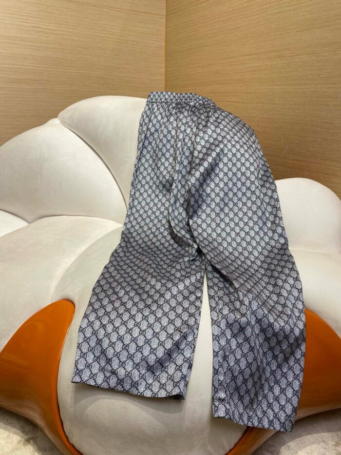 Pantaloni geometrici navy e grigio su sedia floreale bianca, stile casual elegante e confortevole.