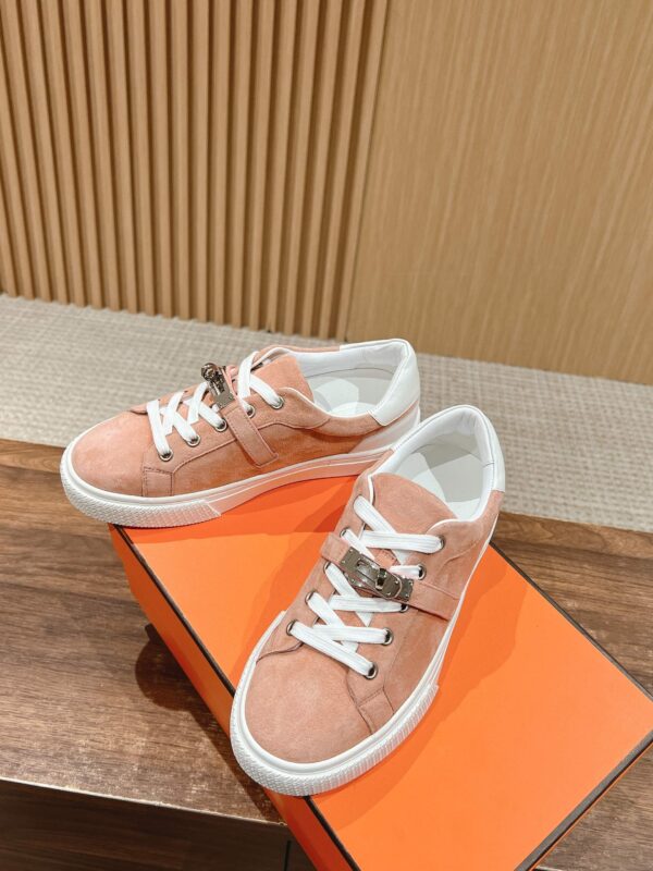 Sneakers in suede pesca con suola bianca, stile casual e trendy su superficie di legno.