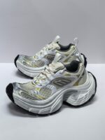 Scarpe da corsa bianco e grigio con dettagli oro, comfort, stabilità e design moderno.