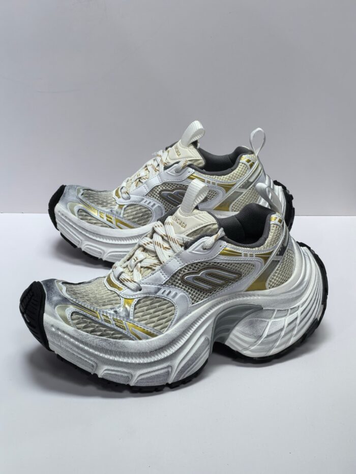 Scarpe da corsa bianco e grigio con dettagli oro, comfort, stabilità e design moderno.
