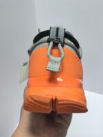 Scarpe da corsa arancioni e grigie con supporto, grip e comfort per runner.