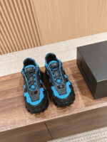 Scarpe da outdoor blu e nere, sporty e resistenti, su superficie di legno con scatola nera.