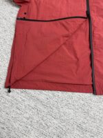 Giacca rossa sportiva impermeabile con zip resistente, ideale per attività allaperto e visibilità.
