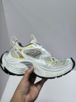 Scarpa da corsa bianca con dettagli oro, tecnologia di ammortizzazione e grip elevato.