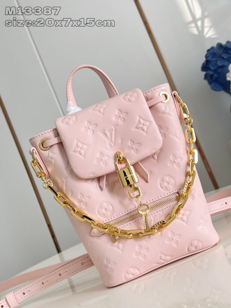 Zaino rosa di lusso con dettagli in oro e tracolla a catena elegante.