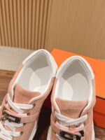 Sneakers rosa in suede con lacci bianchi, dettagli moderni e supporto, stile casual elegante.