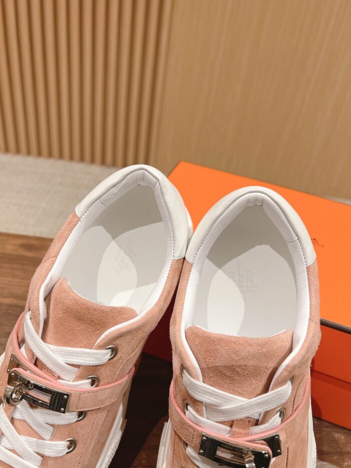Sneakers rosa in suede con lacci bianchi, dettagli moderni e supporto, stile casual elegante.