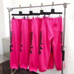 Pantaloni sport rosa con lettere nere, stile urban chic, perfetti per un look trendy e comodo.