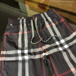Shorts da spiaggia a quadri neri con vita elastica e dettagli verde-bianco.
