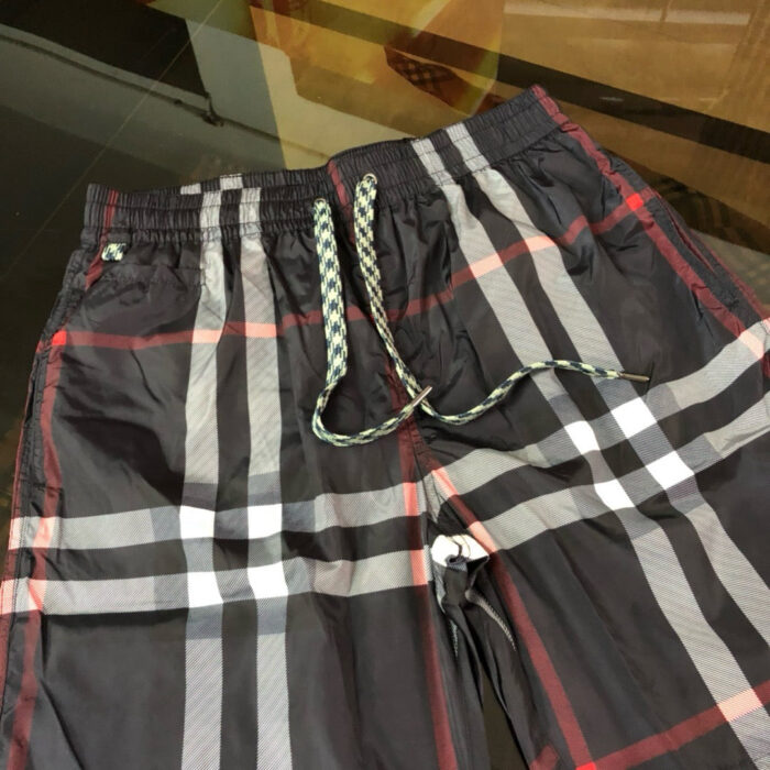 Shorts da spiaggia a quadri neri con vita elastica e dettagli verde-bianco.
