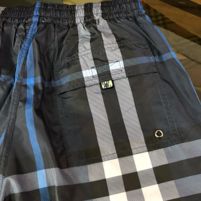 Pantaloncini da spiaggia a quadri blu, grigi e neri con cinturino elasticizzato e tasca funzionale.