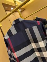 Camicia a quadri moderna, elegante e trendy su appendiabiti dorato, sfondo sfumato caldo.