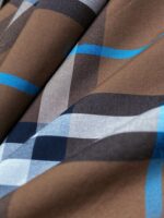 Tessuto a quadri marroni, blu e bianco, versatile per moda e arredamento.