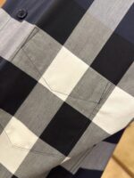 Camicia scozzese grigia e nera, dettagli di alta qualità con bottone navy elegante.