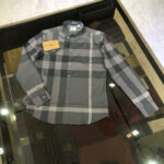 Camicia a quadri grigia classica su tavolo riflettente, stile casual ed elegante.