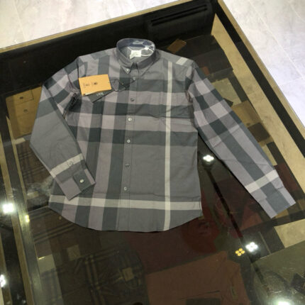 Camicia a quadri grigia classica su tavolo riflettente, stile casual ed elegante.