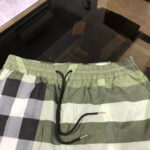Pantaloncini da spiaggia checkered verde e grigio con cinturino elastico e aglet metallico.