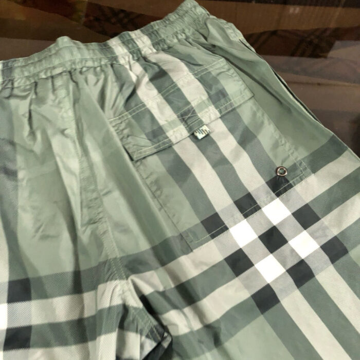 Shorts da spiaggia in tartan verde con cintura elastica e tasca con bottone.