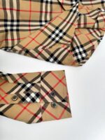 Dettaglio polsino camicia a quadri in tessuto di lusso con bottoni scuri.