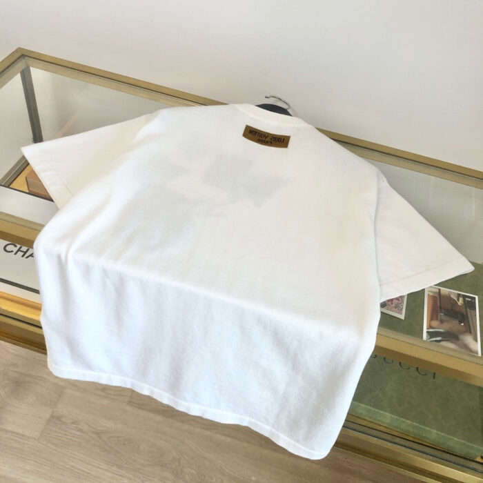 Maglietta bianca minimalista su tavolo di vetro con dettagli eleganti in un ambiente raffinato.