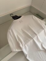 Maglietta bianca classica in cotone su gruccia nera, minimalist style, ideale per outfit casual.