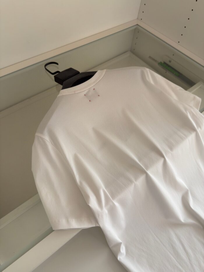 Maglietta bianca classica in cotone su gruccia nera, minimalist style, ideale per outfit casual.