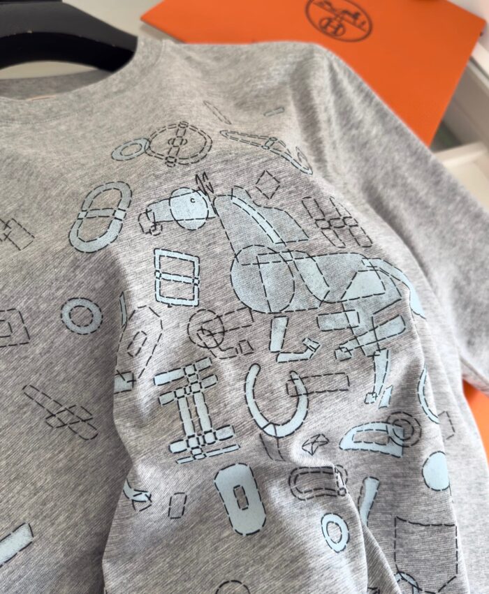 T-shirt grigia con stampa astratta blu, design giocoso e moderno per uno stile casual creativo.
