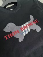 Felpa nera con cane stilizzato, strisce grigie e logo rosso di Thom Browne.