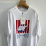 T-shirt bianco con gatto stilizzato, strisce rosse e scritta si-si in blu, stile giovane.