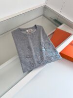 T-shirt grigia con disegni giocosi, esposizione moderna in esposizione minimalista bianca.