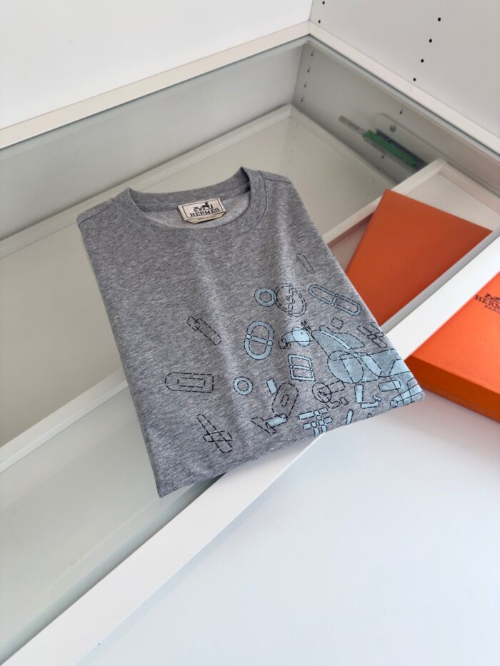T-shirt grigia con disegni giocosi, esposizione moderna in esposizione minimalista bianca.