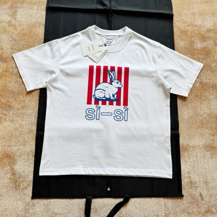 T-shirt bianco con coniglio colorato e dettagli a strisce rosse e bianche.
