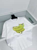 T-shirt bianca con graphic di pantofole banana gialle e dettagli colorati, stile giocoso e trendy.