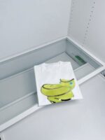Maglietta bianca con divertente grafica di banana colorata, ideale per look casual e giovane.
