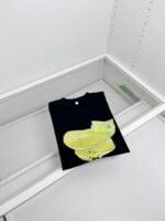 Maglietta nera con scarpe gialle e blu in esposizione su vetrina moderna.