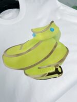 Maglietta bianca con sneakers stilizzati giallo-verde e dettagli blu, stile moda urbana trendy.