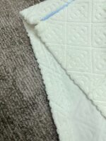 Tessuto trapuntato bianco e sfondo marrone, eleganza e texture per arredi moderni.