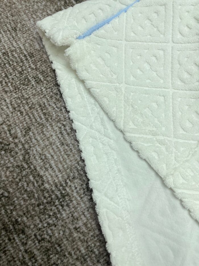 Tessuto trapuntato bianco e sfondo marrone, eleganza e texture per arredi moderni.
