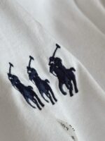 Camicia bianca cotone con ricami navy blu di cavalli in azione, stile polo elegante e casual.