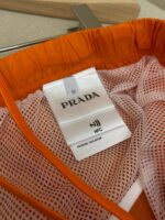 Cappello Prada in nylon arancione con tag NFC, design sportivo e dettagli in mesh breathable.