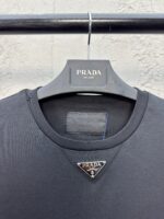 Camicia Prada nera con logo triangolare in metallo, stile elegante e design moderno di lusso.