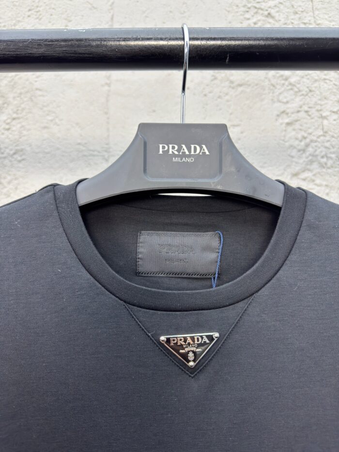 Camicia Prada nera con logo triangolare in metallo, stile elegante e design moderno di lusso.
