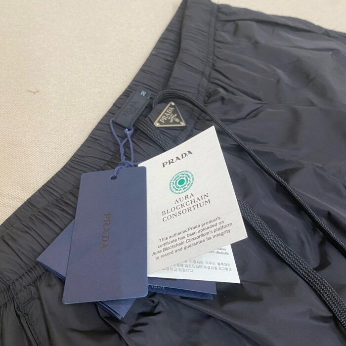 Pantaloni Prada di lusso sostenibili con etichette eco-friendly e dettagli di alta qualità.